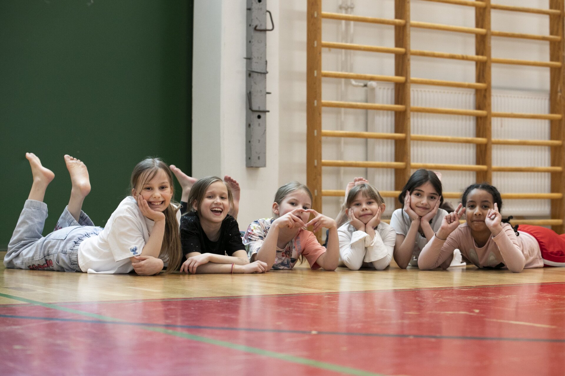 Lapset kyynärnojassa liikuntasalin lattialla.